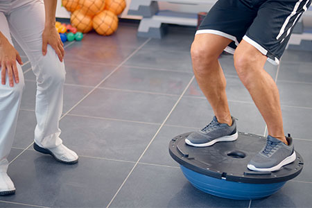 Mature Man Doing Squats and Balancing on Bosu Ball